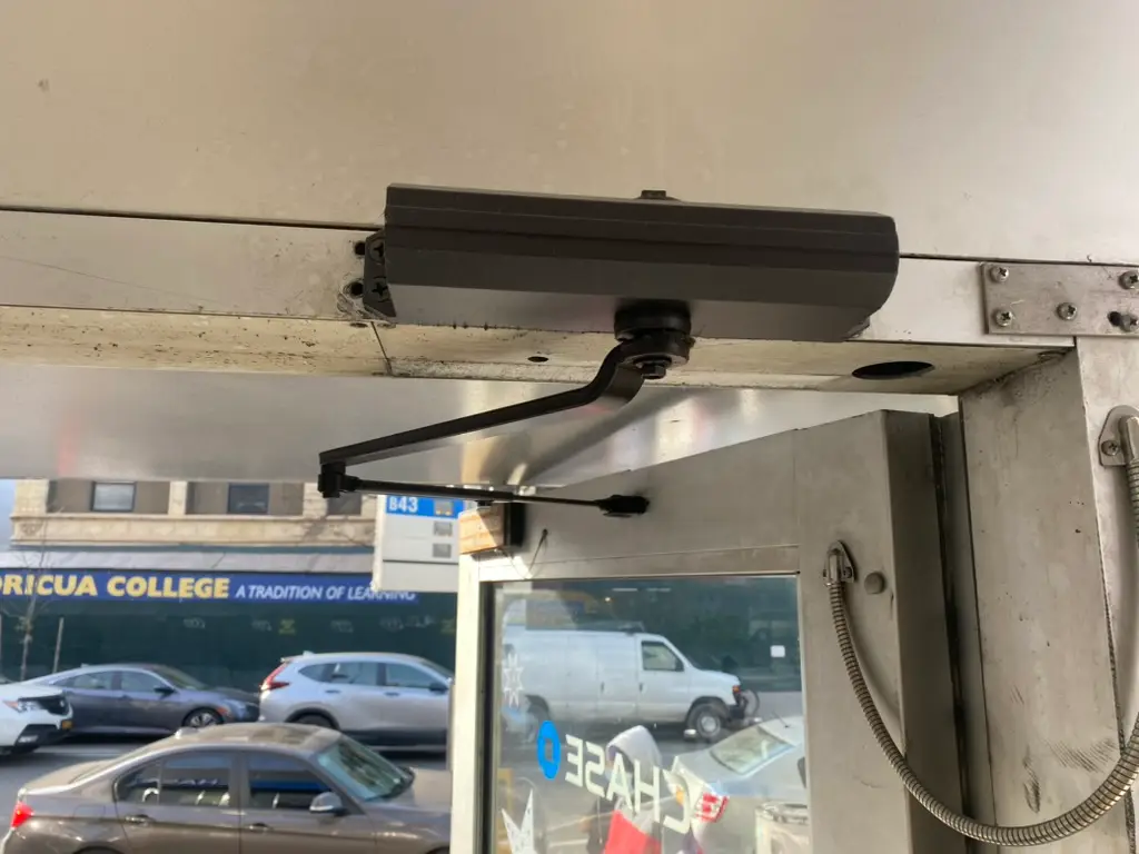 Commercial door closer installed above a glass entry door